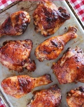 Baked BBQ chicken legs and thighs served on a plate with sauce