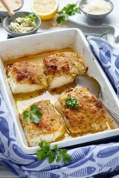 Deliciously seasoned baked fish served on a plate with herbs and lemon.