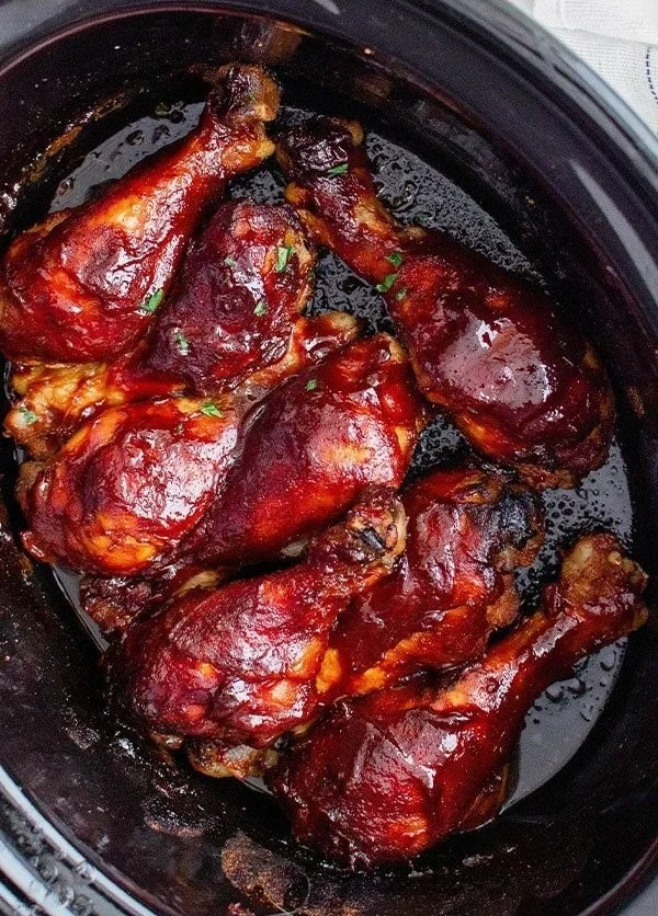 Grilled BBQ chicken drumsticks served on a platter with barbecue sauce.