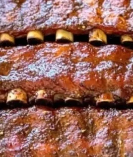 Bobby Flay's dry rub ribs served on a plate with BBQ sauce