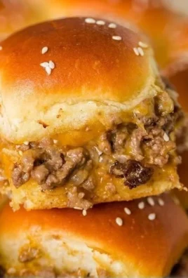 Golden cheeseburger sliders on a plate, garnished with pickles and cheese