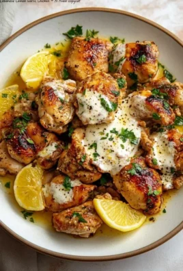 Lebanese Lemon Garlic Chicken served on a plate with herbs and lemon slices.