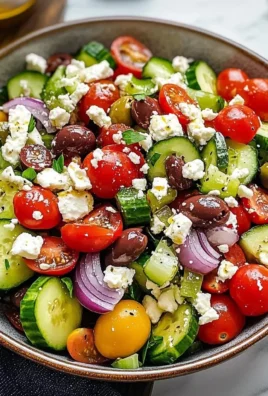 A colorful Greek salad with tomatoes, cucumbers, olives, and feta cheese.