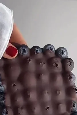 A bowl of Healthy Chocolate Blueberries topped with cocoa and drizzled with dark chocolate.