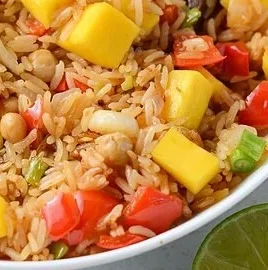 A bowl of Mango Rice topped with fresh mango slices and garnished with herbs.
