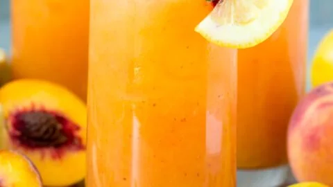 Refreshing Peach Lemonade served in a glass with fresh peaches and lemons