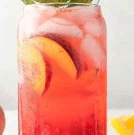 Refreshing Raspberry Peach Lemonade Cooler in a glass with ice and fruits