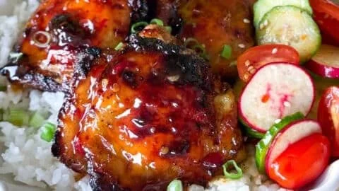 Sticky sweet chili chicken thighs cooked in an air fryer, garnished and ready to serve.