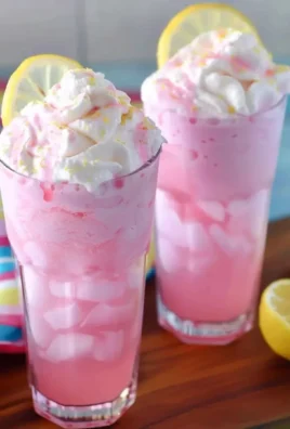 Glass of creamy whipped pink lemonade topped with lemon slices and mint