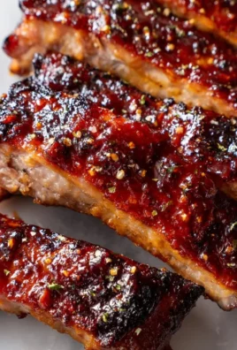 BBQ Baby Back Ribs with sticky glaze on a grill, showcasing deliciousness.