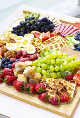 Beautifully arranged brunch charcuterie board with meats, cheeses, and fruits.