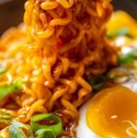 Bowl of creamy Buldak Cheese Ramen topped with green onions and cheese