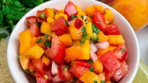 Bowl of easy homemade fresh peach salsa with colorful ingredients