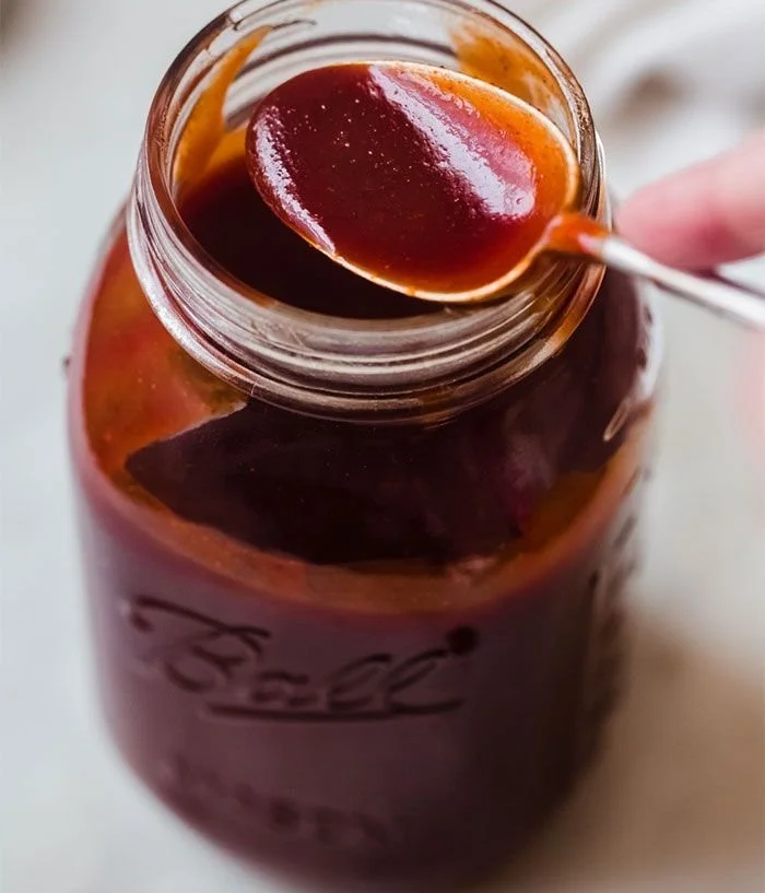 Homemade BBQ sauce in a jar with fresh ingredients around it