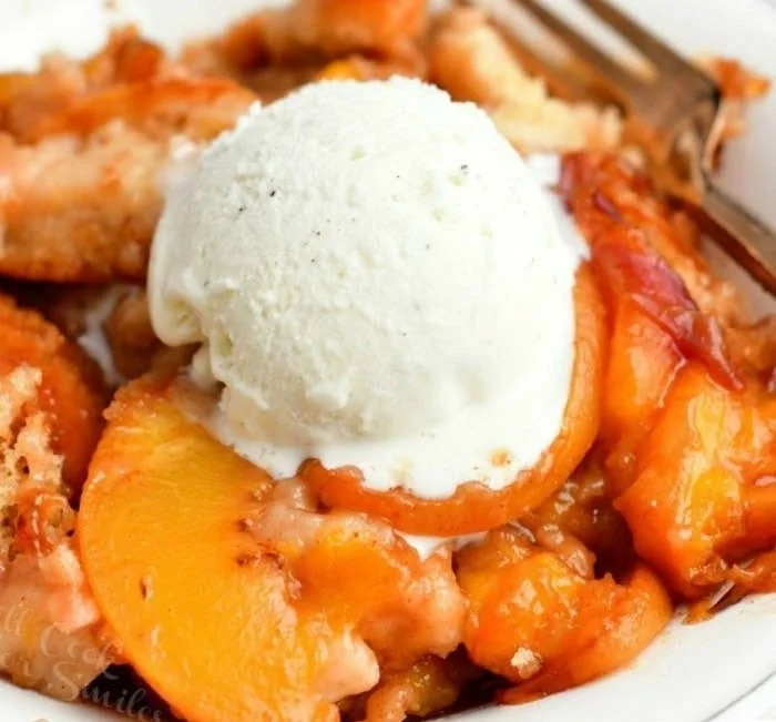 Delicious homemade Peach Cobbler served in a rustic dish with fresh peaches