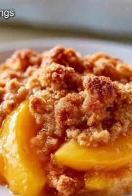 Homemade Peach Crisp dessert topped with oats and brown sugar, served in a bowl.