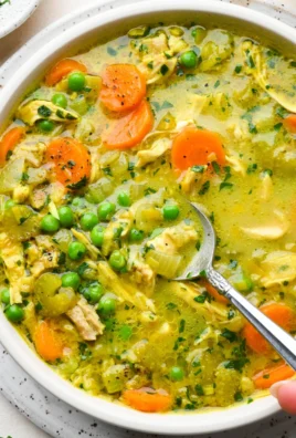 Bowl of anti-inflammatory turmeric chicken soup garnished with herbs
