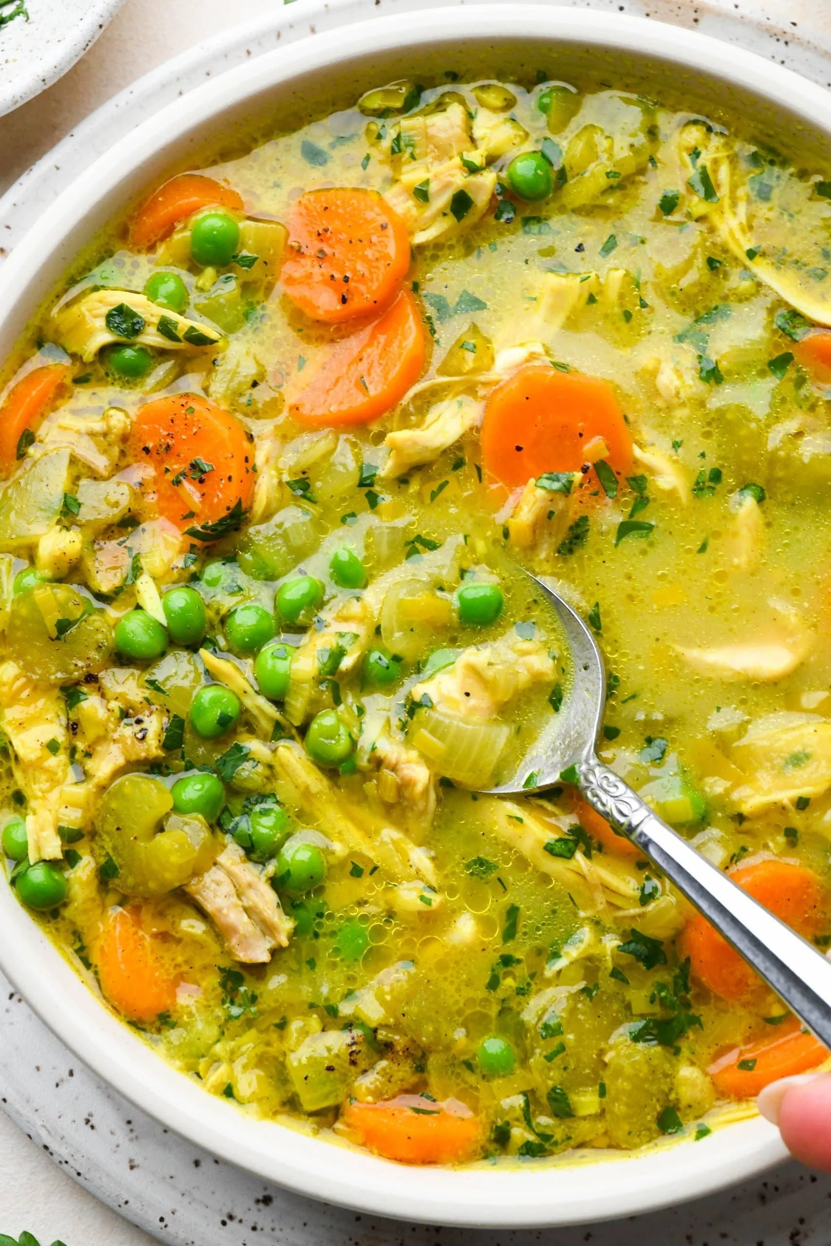 Bowl of anti-inflammatory turmeric chicken soup garnished with herbs