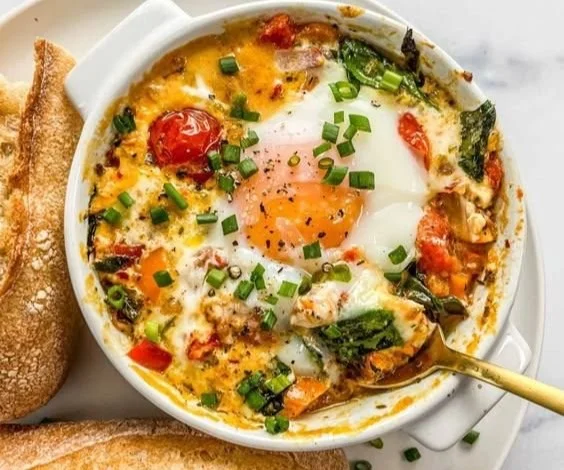 Baked feta eggs with tomatoes and spinach in a serving dish