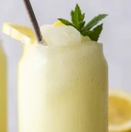 Boozy frozen lemonade served in a glass with lemon slices and ice.