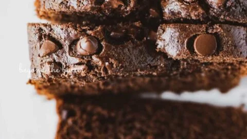 Moist chocolate zucchini bread with chocolate chips on a wooden table