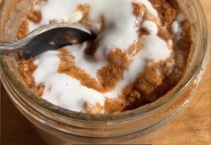 Bowl of cinnamon roll overnight oats topped with spices and nuts