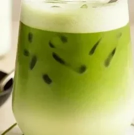 Iced matcha latte in a glass with green tea powder and milk.