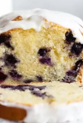Sliced lemon blueberry pound cake with fresh blueberries and lemon zest