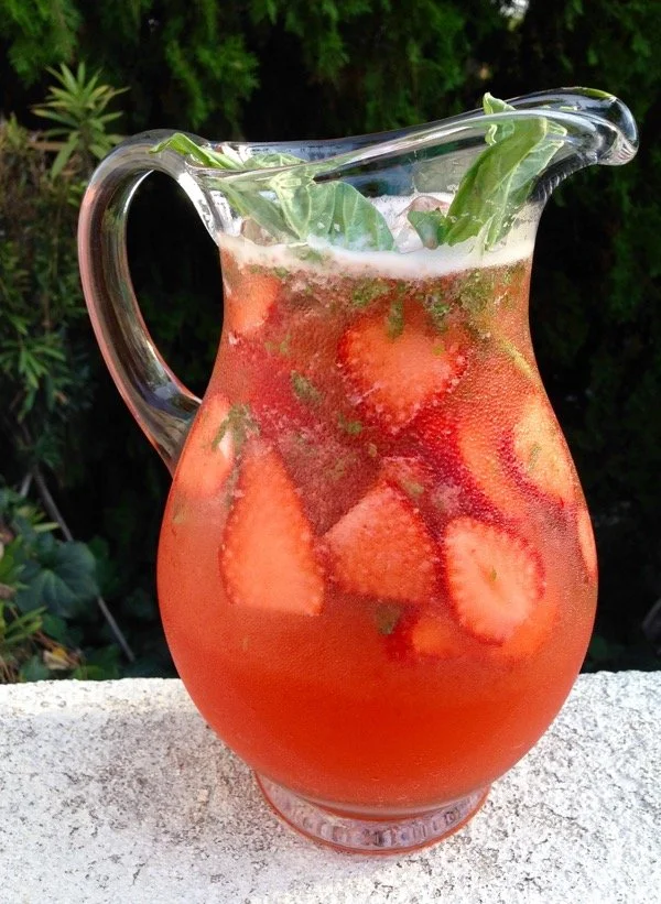 A refreshing glass of Strawberry Basil Lemonade garnished with fresh strawberries and basil.