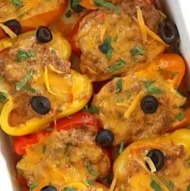 Stuffed taco peppers with ground meat and cheese topped with herbs in a dish