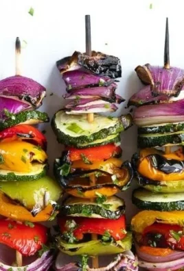 Colorful veggie skewers with bell peppers, zucchini, and mushrooms on a grill.